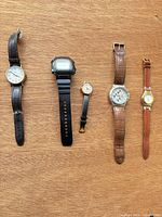 Five watches laid out side by side on wooden surface