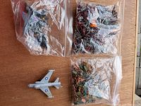Overview of loose grey fighter jet and three bags of mixed toy soldiers and aircraft parts