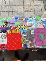Top view showing assortment of colourful small and medium paper gift bags with various prints and handle styles