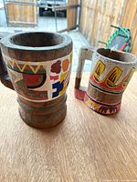 Both wooden mugs on tabletop showing size, form and paint schemes