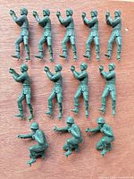 All twelve green plastic soldier figures laid out, eight standing and four kneeling
