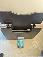 Folded black Varidesk tray table with accessory board placed beneath