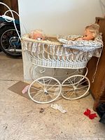 Full view of wicker baby carriage with two dolls inside