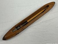 Full view of wooden weaving shuttle with bobbin inside