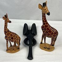 Group shot of two giraffe figures and elephant wall carving