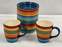 Canister with lid in place alongside two matching mugs