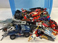 Overall lot view with blue storage bin spilling assorted LEGO pieces and partial models
