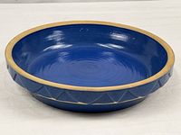 Top angled view showing blue glazed stoneware pie dish with natural rim and exterior pattern