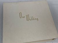 Closed album showing cream cover stamped Our Wedding