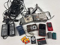 Overall lot showing cameras, camcorders, adapters, charger, batteries, memory cards and cables