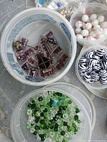 containers with various green, purple, zebra striped beads and findings