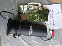 Black cylindrical speaker, mirrored rectangular accessory, handwritten lot note visible