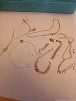 Five anklets laid out showing designs and charms