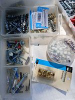 Assorted screws, anchors, brass grommet set and cable clips in compartment box