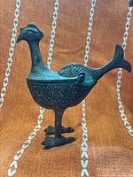 Side view of bird-form bronze vessel showing overall design and patina