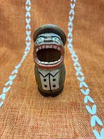 Front view of carved wood figurine showing open mouth, painted jacket and shirt