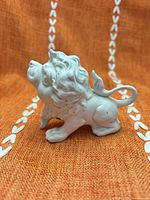 Side view of glossy white ceramic lion figurine