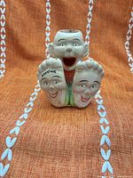 Front view showing laughing child figure, two faces on feet, open mouth holder