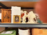 Shelf with wooden luminaria, framed picture, porcelain nativity camel and child, ornaments, candle