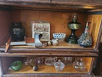 cabinet shelves showing stereoscope, glass items, birds, vases