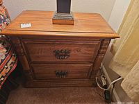 Front view showing two drawers, brass-tone pulls, turned column accents
