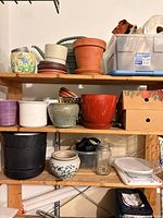 Shelving unit with assorted planters, saucers, jars and containers
