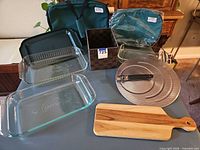 All items laid out: two Pyrex dishes, two carriers, lids, splatter screen, cutting board, basket