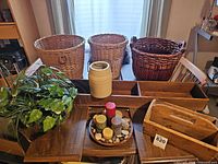 Overview of lot showing three wicker baskets, two long wooden trays, wooden caddy, stoneware crock, candle tray with candles and stones, faux plant