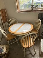 Table and three of the chairs against wall under window