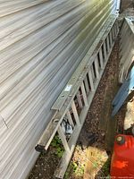 Full view of aluminum extension ladder leaning against siding