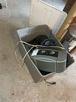 Overall view of grey storage tote containing Honeywell air purifier and other small fans