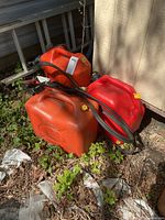 three fuel cans with booster cables on top
