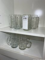 Shelf view showing four Coca-Cola glasses and two Billy Bee mugs