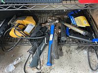Lot on wire shelf showing Dewalt jigsaw, bow saw, multiple hammers