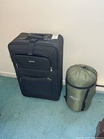 Suitcase next to sleeping bag showing size and color