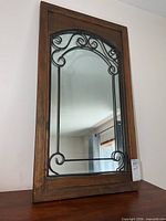 Front view of mirror showing wood frame and metal scrollwork