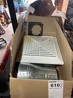 Open box showing exhaust fan grille, housing and duct elbow