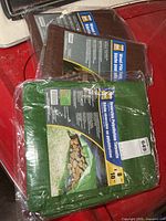 Three packaged tarps showing labels and sizes