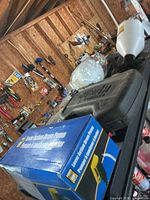 Overall view of drum pump box, Wizard case, sprayer and saw blades on shelf