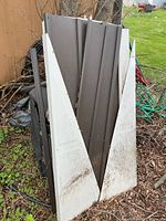 Stack of brown corrugated steel panels and white triangular gable panels