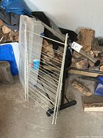 All three items leaning against wall: tote, drying rack, garment rack