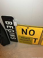 All three metal signs leaning against wall: Begins, No Exit, Private Property No Trespassing