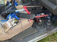 Passenger seat contents including straps, bow saw, solar charger, gloves, compressor and cables