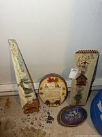group shot of four wall art items: painted saw, round live-edge plaque, rectangular sign, oval wolf plaque