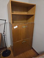 Full view of tall two-section cabinet showing open top shelves, middle and lower doors