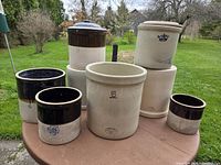 Group shot of nine assorted stoneware crocks on outdoor table