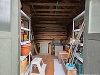 view into shed showing lumber, shelving with pots, patio furniture pieces