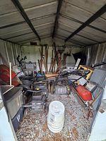 Overall view of shed showing lawn mowers, hand tools, shelving, containers