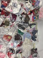 Overview of numerous bagged Barbie clothes and accessories spread out