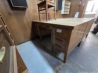 Desk full view showing drawers and legs, chair placed on top
